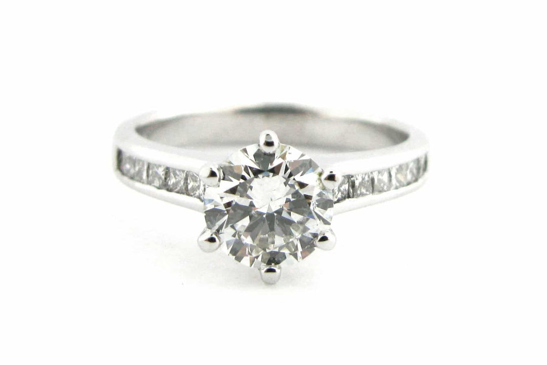 Six claw set round brilliant cut diamond ring with channel set diamonds