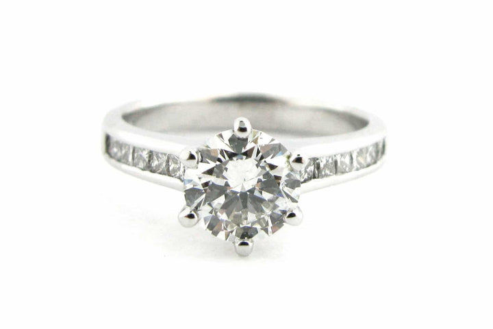 Six claw set round brilliant cut diamond ring with channel set diamonds