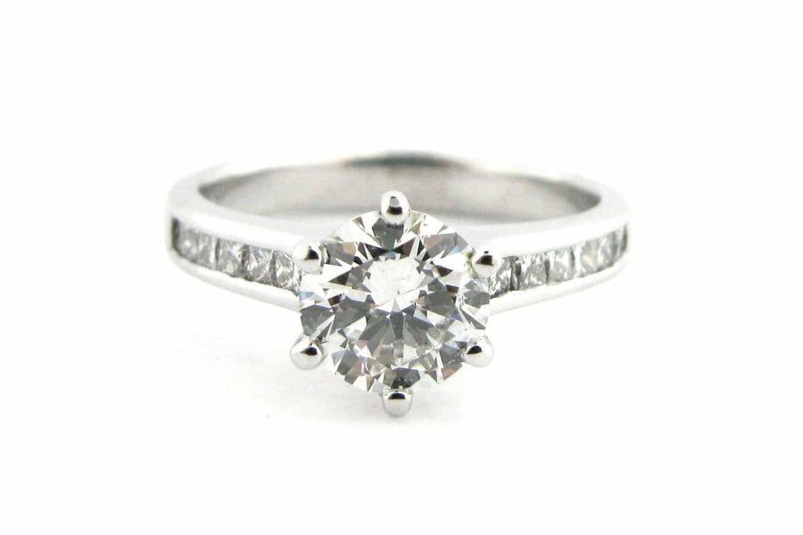 Six claw set round brilliant cut diamond ring with channel set diamonds