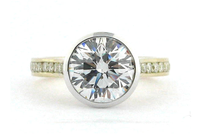 Two tone bezel set round brilliant cut ring with channel set diamond band