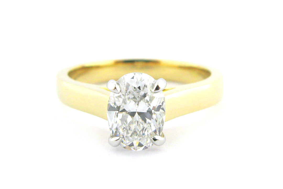 Two tone gold ring with four claw set oval diamond