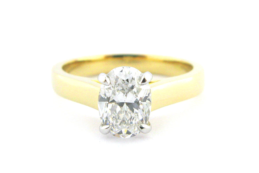 Two tone gold ring with four claw set oval diamond