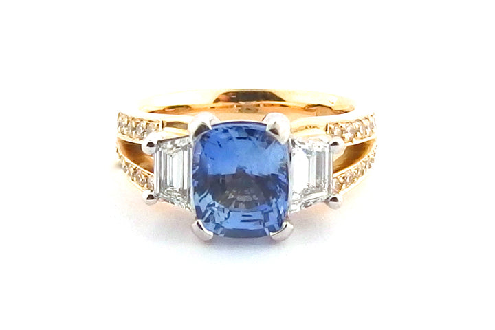 Three stone ring with a cushion cut sapphire and a split band