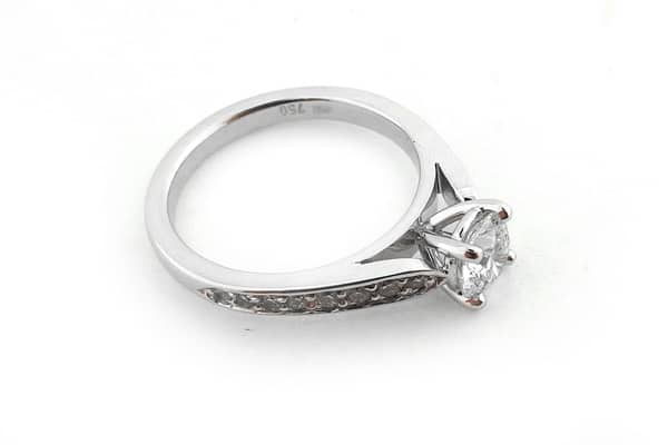 Four claw set round brilliant cut diamond ring with graduated bead set diamonds