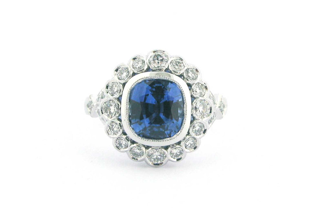 Cushion cut sapphire with a halo of bezel set diamonds