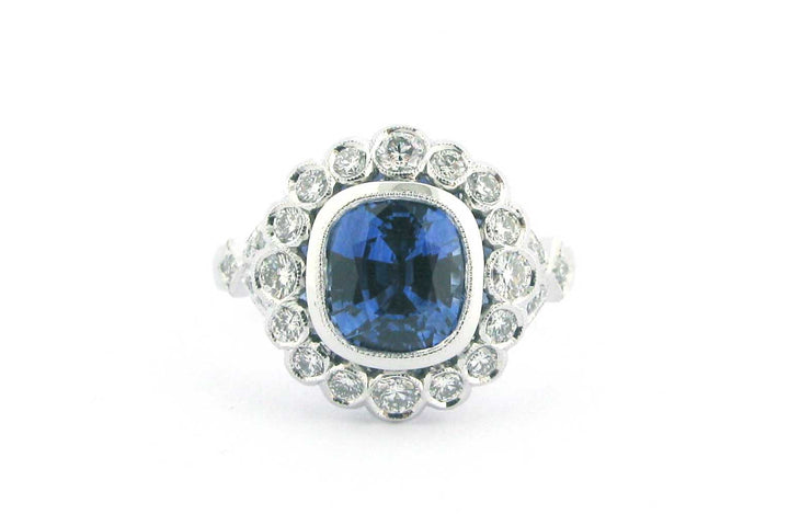 Cushion cut sapphire with a halo of bezel set diamonds