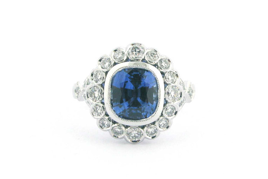 Cushion cut sapphire with a halo of bezel set diamonds