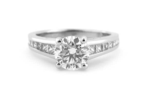 Round brilliant cut four claw set ring with graduated princess cut diamonds