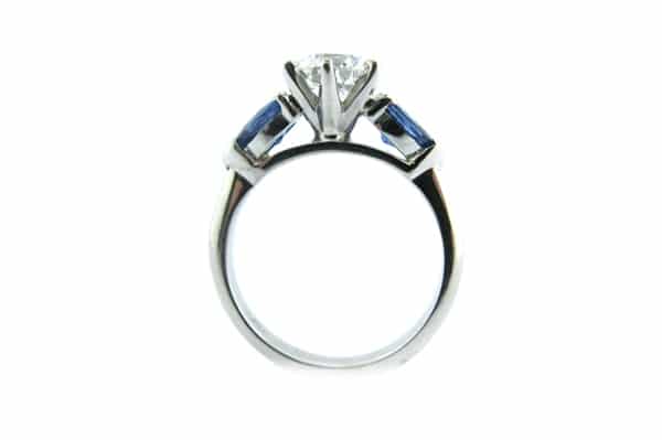 Six claw set round brilliant cut diamond with pear shape sapphire sides