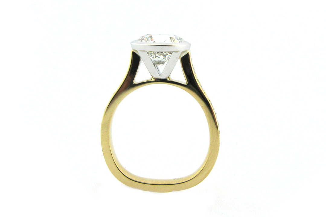 Two tone bezel set round brilliant cut ring with channel set diamond band