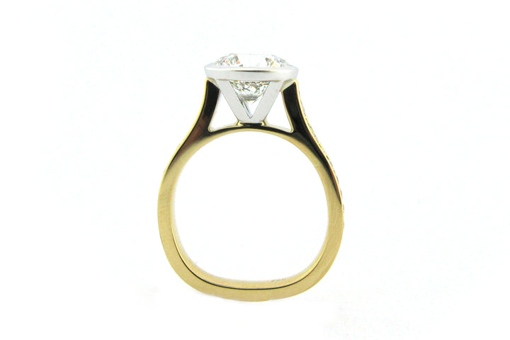 Two tone bezel set round brilliant cut ring with channel set diamond band