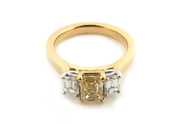 Yellow emerald cut diamond ring with two white emerald cut side diamonds