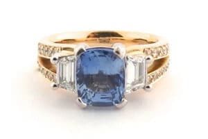 Three stone ring with a cushion cut sapphire and a split band